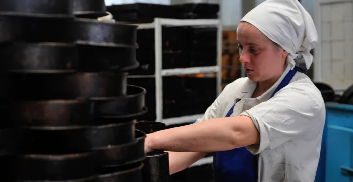 Young woman cleaning cake moulds.