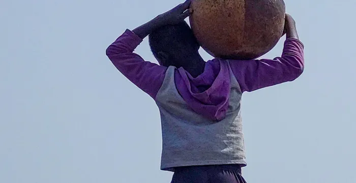 Child carries a bucket in a mine