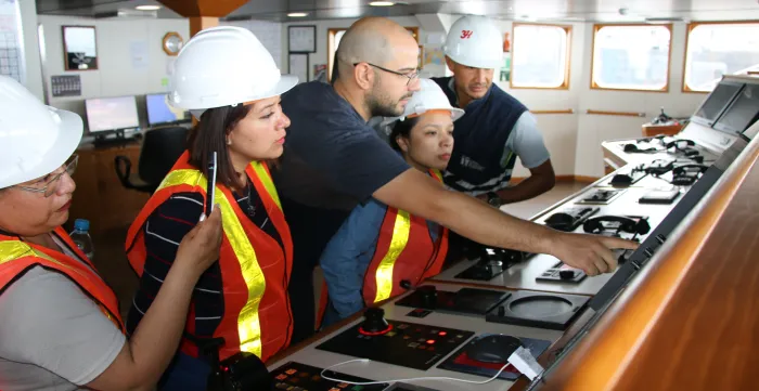 Personas vestidas de inspectores mirando el panel de control en la cabina de un buque pesquero