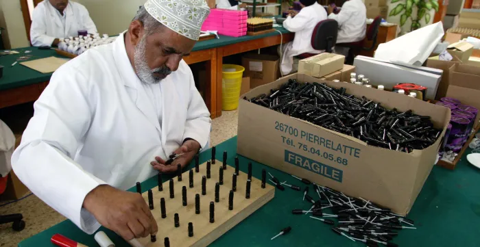a man packaging plant for Amouage perfume bottles
