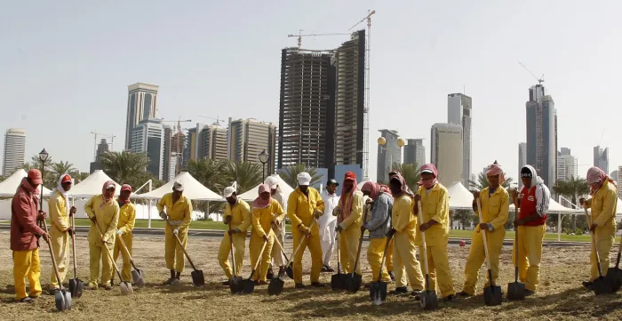 Migrant workers dig into a field in Doha, Qatar