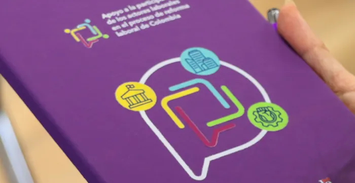 Manos en primer plano de una mujer sosteniendo una agenda con la marca del proyecto