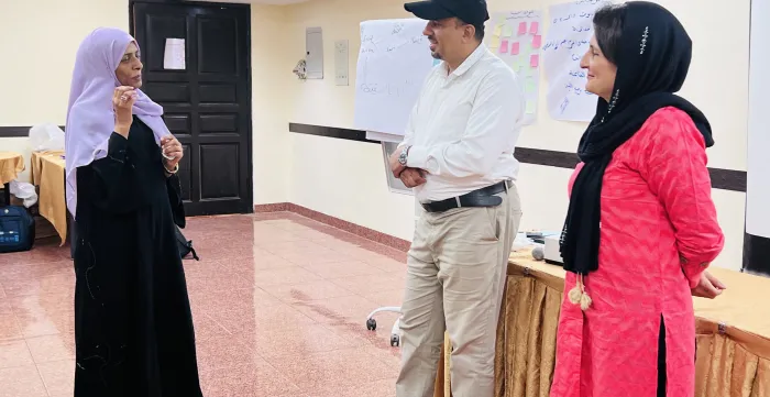a veiled lady discussing with 2 trainers during the SYIB training 