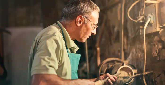 Senior male turner working on lathe machine in workshop