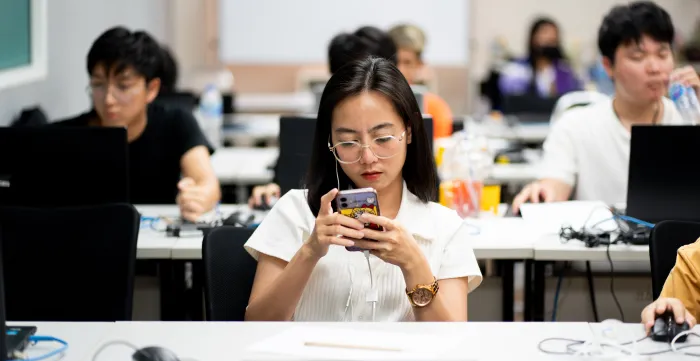 Woman looking at her phone during a digital content creator course in Bangkok