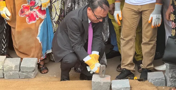 Man in a suit using a hammer to set a paving stone