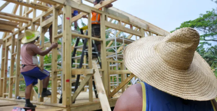 Group of unrecognizable Pacific islanders builders building a new local traditional architecture residential wooden home in Rarotonga, Cook Islands