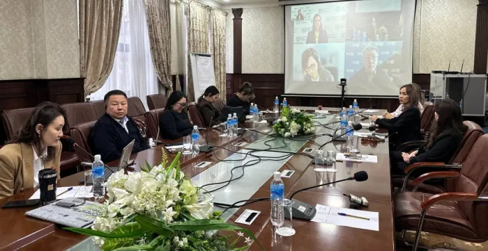 People sitting at a table looking at a big screen