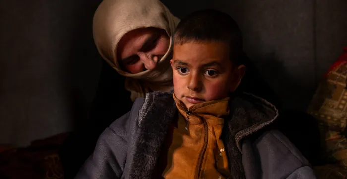 Syrian agricultural worker Aisha Al Mohammed and her youngest son sit inside a tent in their informal settlement in Lebanon’s Bekaa Valley. December, 15, 2025 