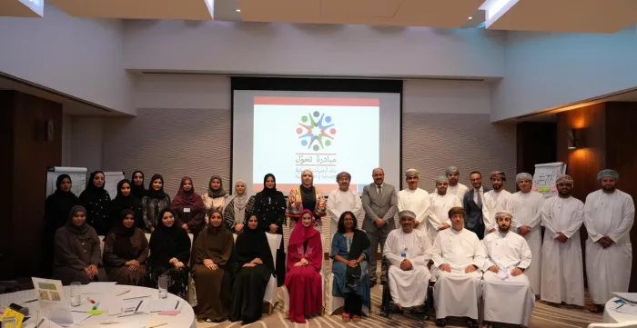 A group of men and women pose for a photo after training in Oman