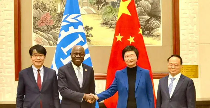 Gilbert F. Houngbo, Director-General of the ILO, with Wang Xiaoping, Minister of Human Resources and Social Security of China shaking hands in front of their flags