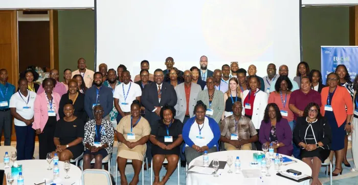 A large group of workshop participants, men and women of diverse ages pose together for a group photo in a conference room