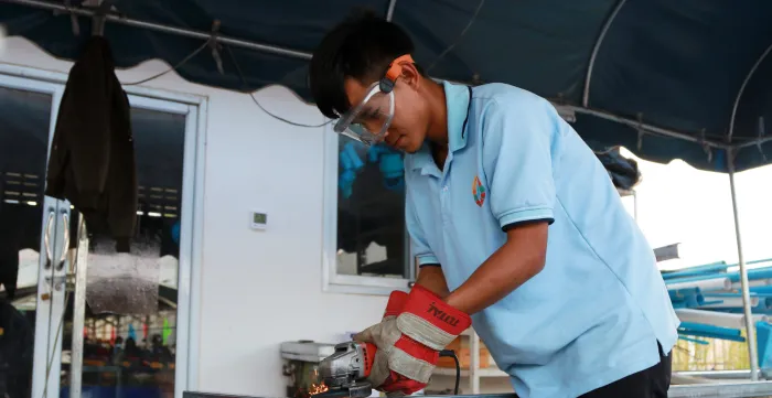 A male worker uses equipment to cut iron.
