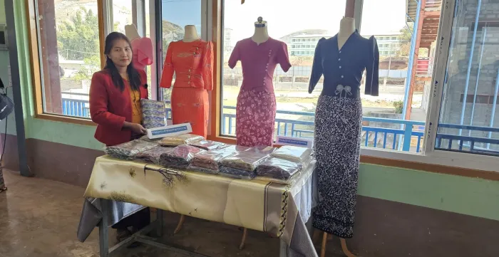 Dresses and Burmese longyi made by sewing and weaving training programme participants are being displayed at the sideline of closing ceremony of vocational training.