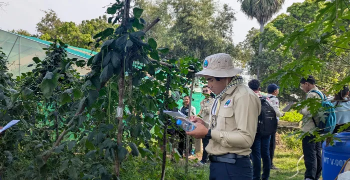 A man surrounded by plants writing in a notebook.