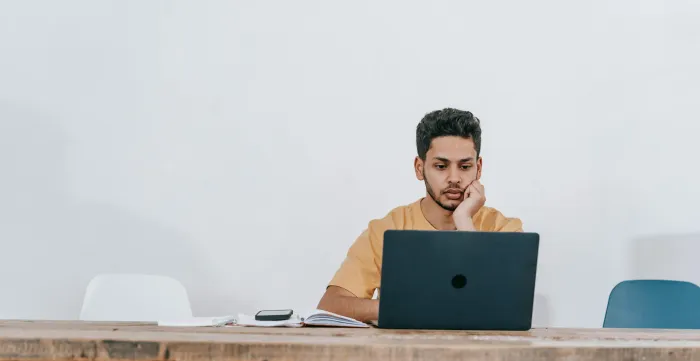 A young man sitting on a table with a laptop