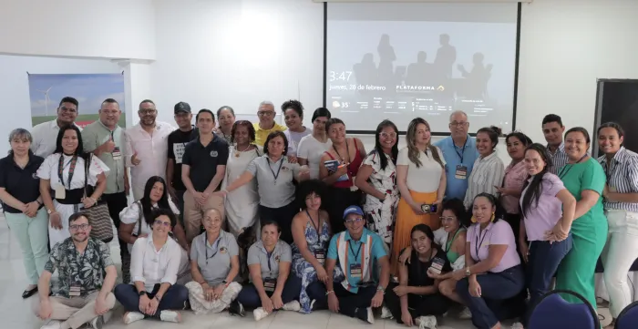 Grupo numeroso de personas posando para una foto grupal en un salon 