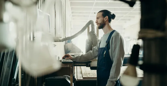 A factory worker stands in front of a computer