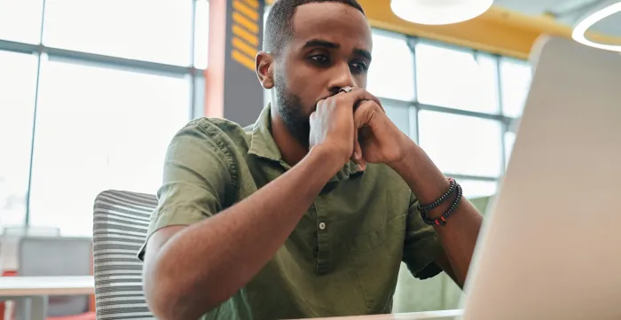 mas stressed looking at his laptop, with his hands resting on his chin.