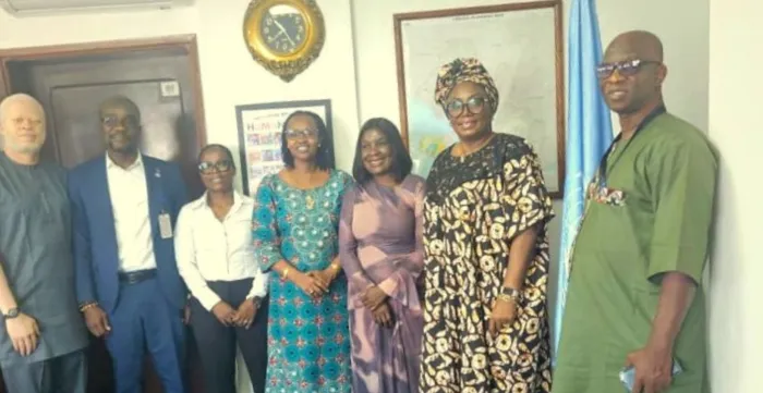 A group of officials pose inside an office near the Liberian and United Nations flags. The participants are gathered following a meeting focused on employment, labour reform, and inclusive development initiatives in Liberia.