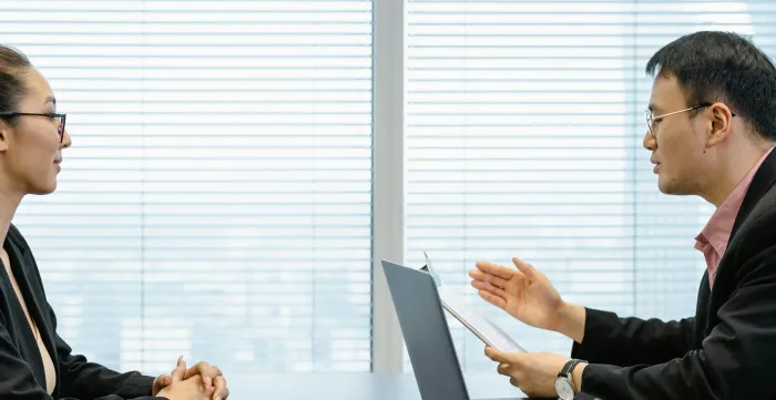 Two businesspeople engaged in a discussion during a professional meeting in an office setting