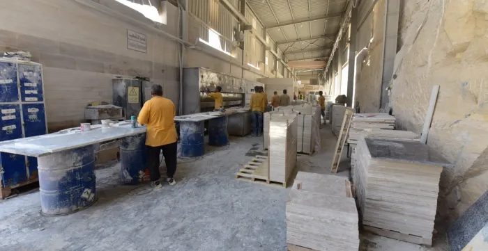 Workers in a marble-processing enterprise work along the production line of the "Finishing Department".