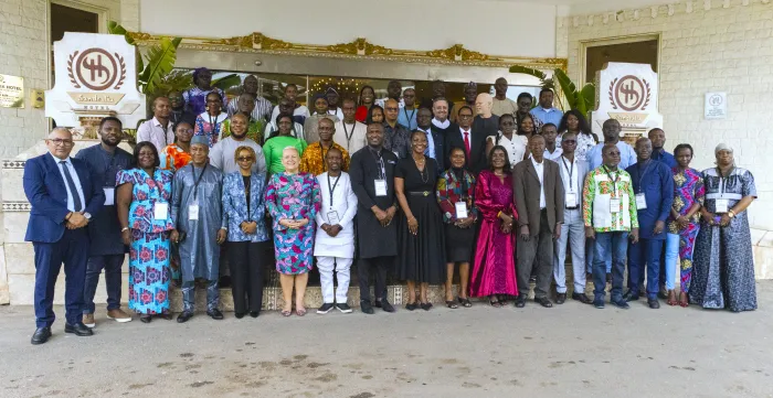 Large group photo of participants standing outside a hotel venue after a workshop or conference.