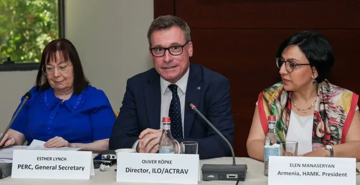 Three people sitting at a table with mics in front of them