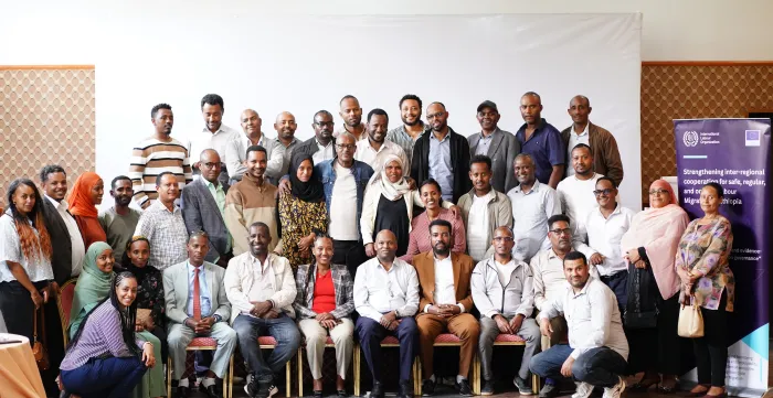 Group photo of workshop participants standing and seated beside an ILO and European Union project banner.