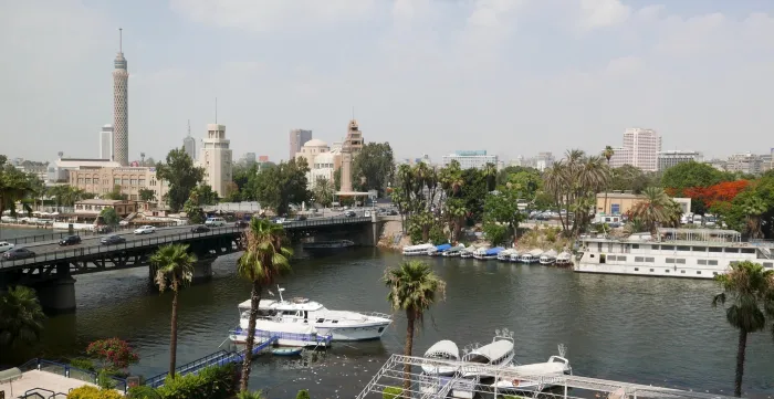 A birds-eye view of Egypt's Nile River showing a cruise boat in the water and restaurants and hotels.