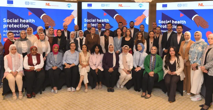 Around 40 participants in a training workshop pose for a commemorative group photo in Egypt, standing in front of training screens.