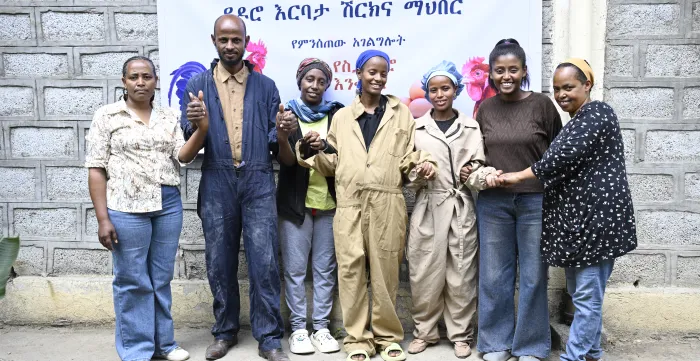 young men and women standing outside their cooperative poultry farm