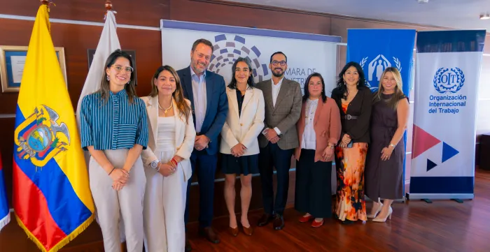 Grupo de ocho personas posa frente a los estandartes de la OIT, ACNUR y la Cámara de Industrias y Producción.
