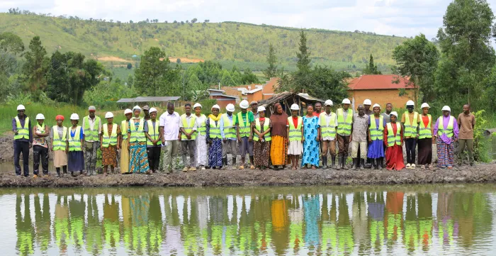 labour based fish farming trainee workers standing across the fish pond