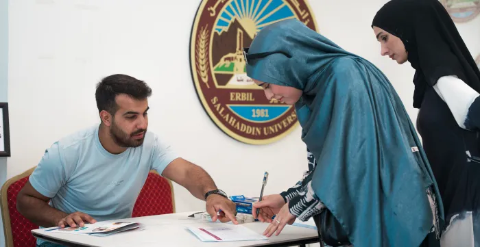 two female students signing at the registration desk 