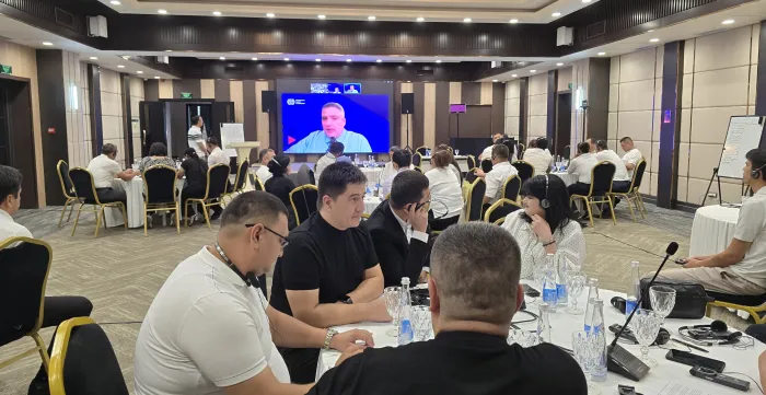 Participants seated around tables in a conference room