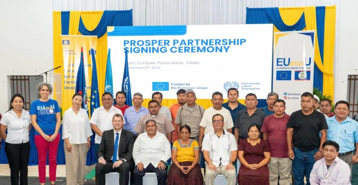 A group of persons standing in rows in front of a large sign