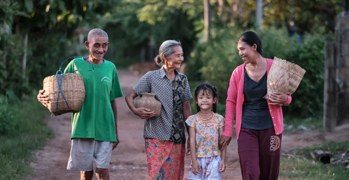 Three generations of a family walk together along a rural road.
