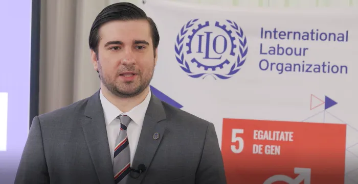 Man speaking in front of ILO banner