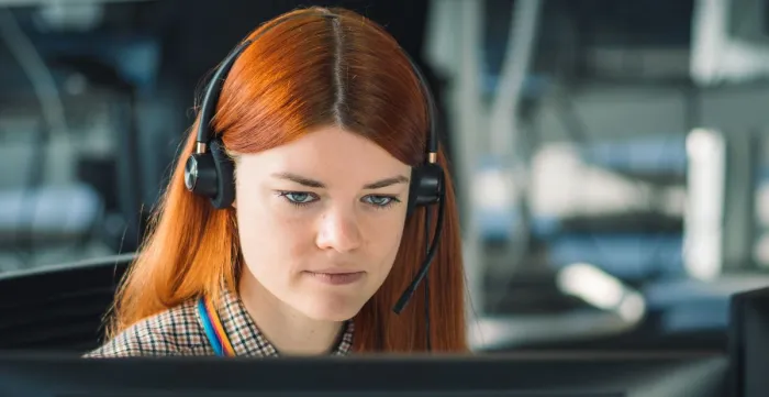 Young woman with a headset in front of a computer 