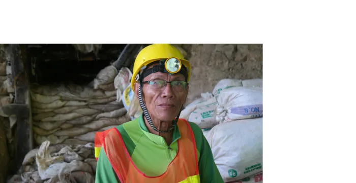 A worker in mining wearing a yellow hard hat.