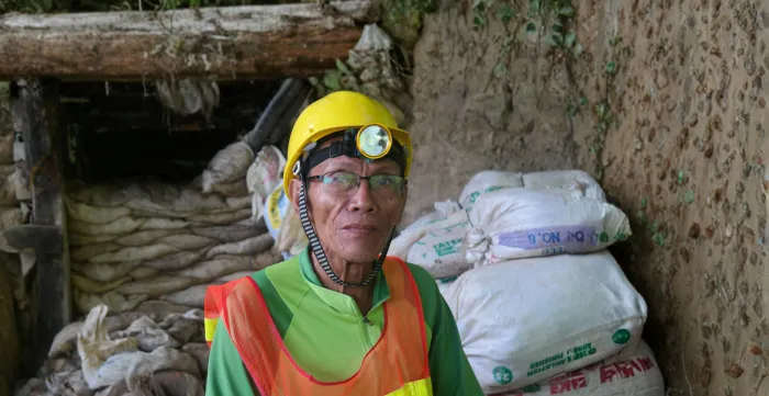 A worker in mining wearing a yellow hard hat.