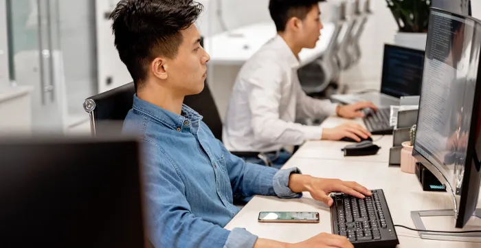 Young professionals working on computers in a modern office environment, focused on their tasks.