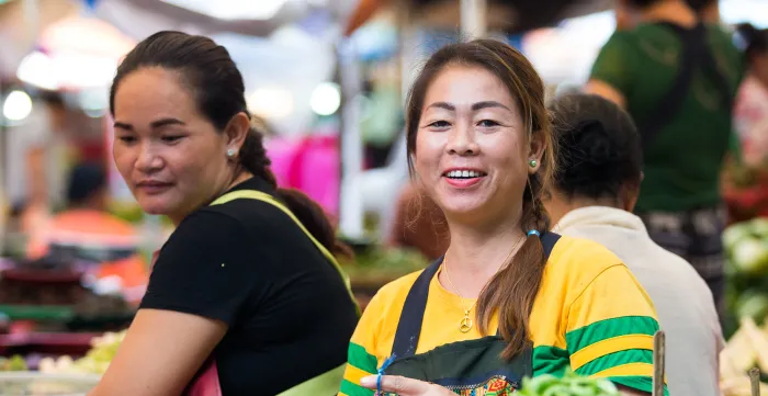 Two women sell fresh vegetables at a market. 