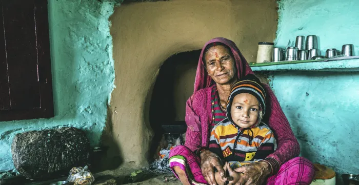 A woman with hijab holding a young child inside a traditional home.