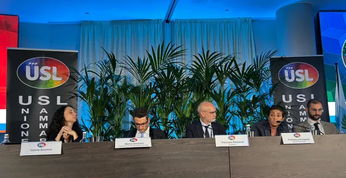 Five persons sitting at a congress desk while one of them is speaking.