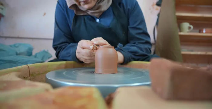 A woman shapes a ceramic piece at a pottery wheel during a visit to a women-led ceramics initiative in Petra, Jordan.
