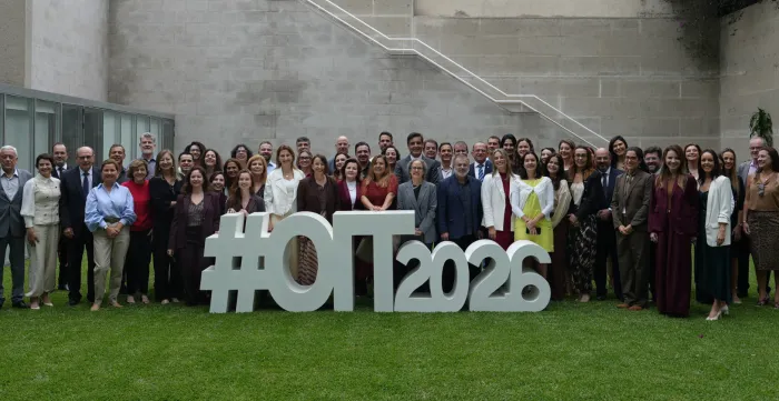 Grupo de pessoas posa diante de escultura na qual se lê OIT 2026 localizada no Escritório Regional da OIT em Lima. 