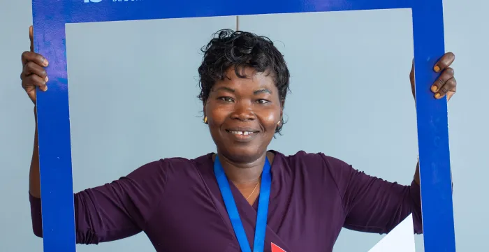 Léontine Gbati, travailleuse domestique au Togo et participante au Forum de Dakar, pose devant le cadre officiel de l’événement.