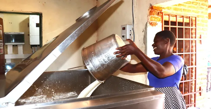 Woman throwing milk into machine, Malawi